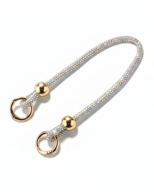 A clear mobile phone case with a luxury rhinestone lanyard attached to it, featuring a sparkling strap and rhinestone clasps.