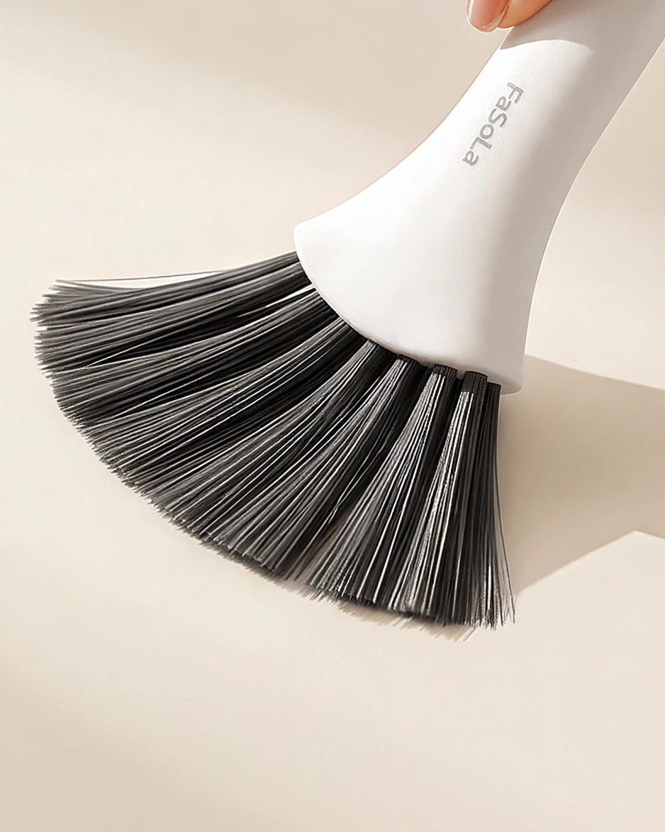 A close-up of a hand holding a white and black bristle brush against a warm beige background, with promotional text reading 'Dense Bristles No Shedding' and smaller copy about securely locked bristles staying put.