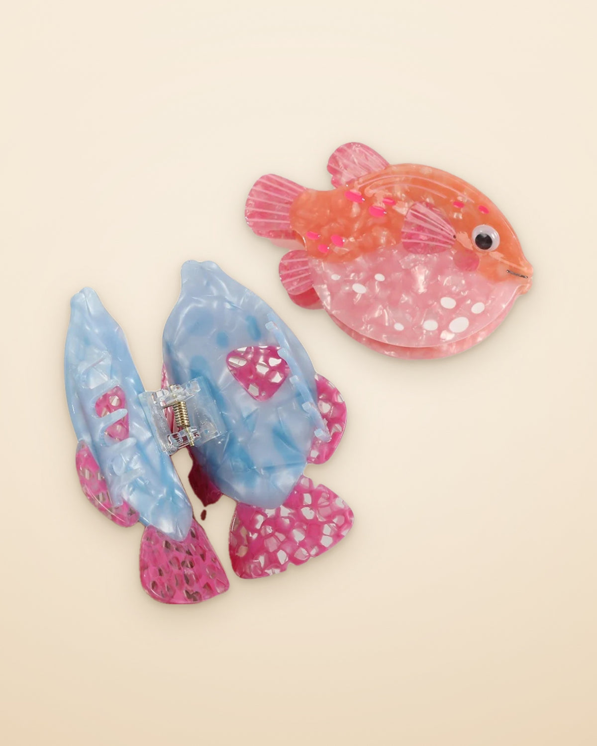 Blue Lagoon Fish claw clip shown open beside the Coral Pufferfish on a sand background