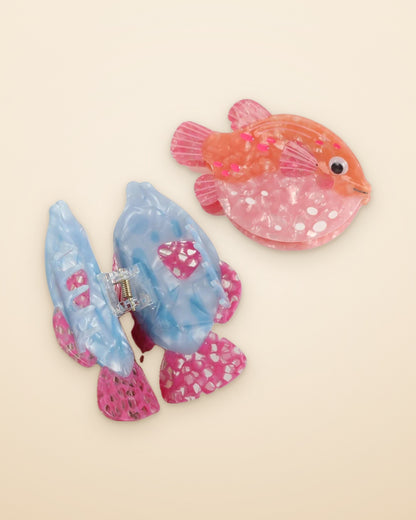 Blue Lagoon Fish claw clip shown open beside the Coral Pufferfish on a sand background