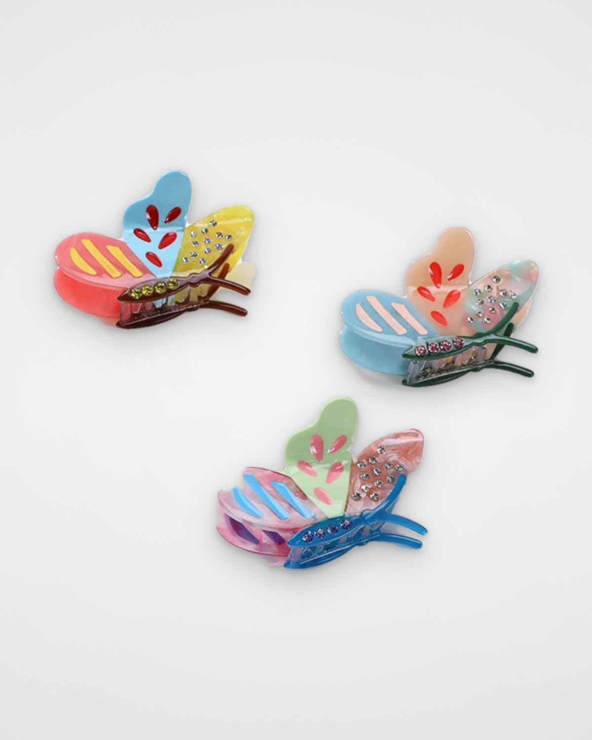 Patchwork butterfly acetate claw clips — Tropical Sunset, Cotton Candy Sky and Lilac Meadow on a light gray background