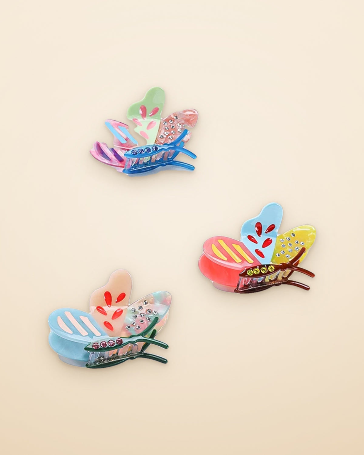 Three patchwork butterfly claw clips on a sand background