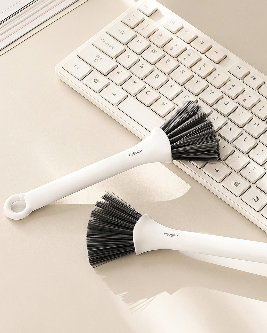 Two FaSoLa crevice brushes resting on a desk beside a keyboard