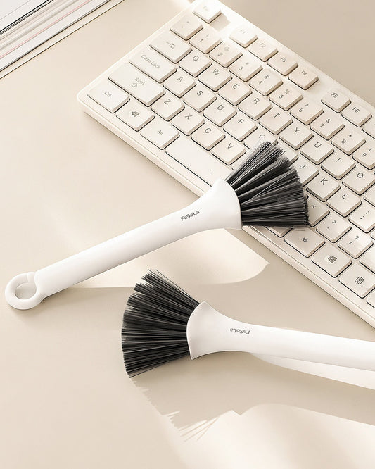 Two FaSoLa crevice brushes resting on a desk beside a keyboard