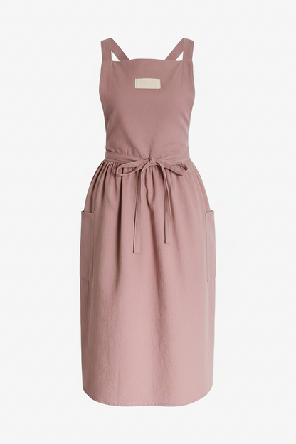 A dusty pink sleeveless apron with adjustable shoulder straps, a tie waist, and side pockets, shown against a plain white background.