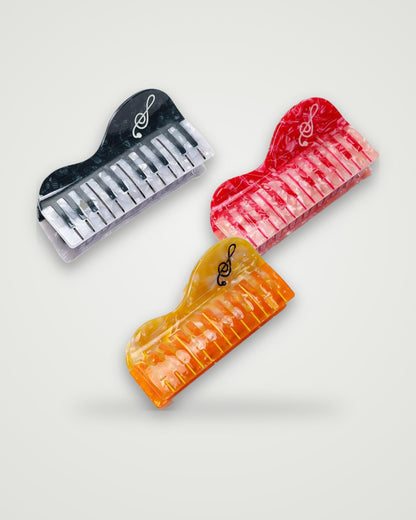 Piano acetate claw clips in Marmalade Grand, Cherry Sonata and Midnight Keys on a light gray backdrop